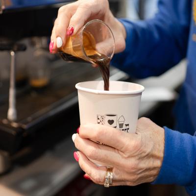 Shot of espresso being poured into a paper cup.