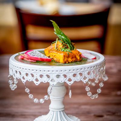 Spiced, pan-fried paneer on a decorative stand with dragon fruit slices.