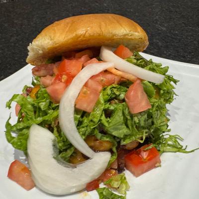 Burger topped with lettuce, tomatoes, and onion.
