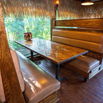 A rustic restaurant booth with tan seating and thatched roofing.