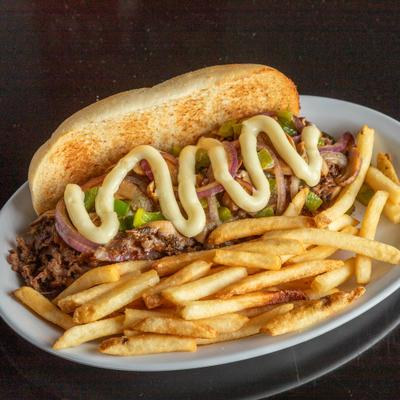 Philly cheesesteak sandwich served with fries on a white plate.