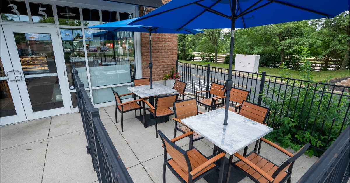 Exterior, covered seating area, marble top tables with chairs under parasols, metal railing