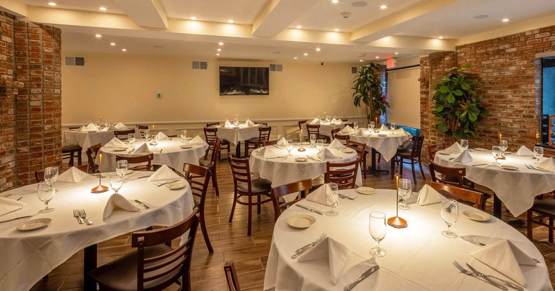 Interior, dining area, round white cloth tables ready for guests, red brick walls