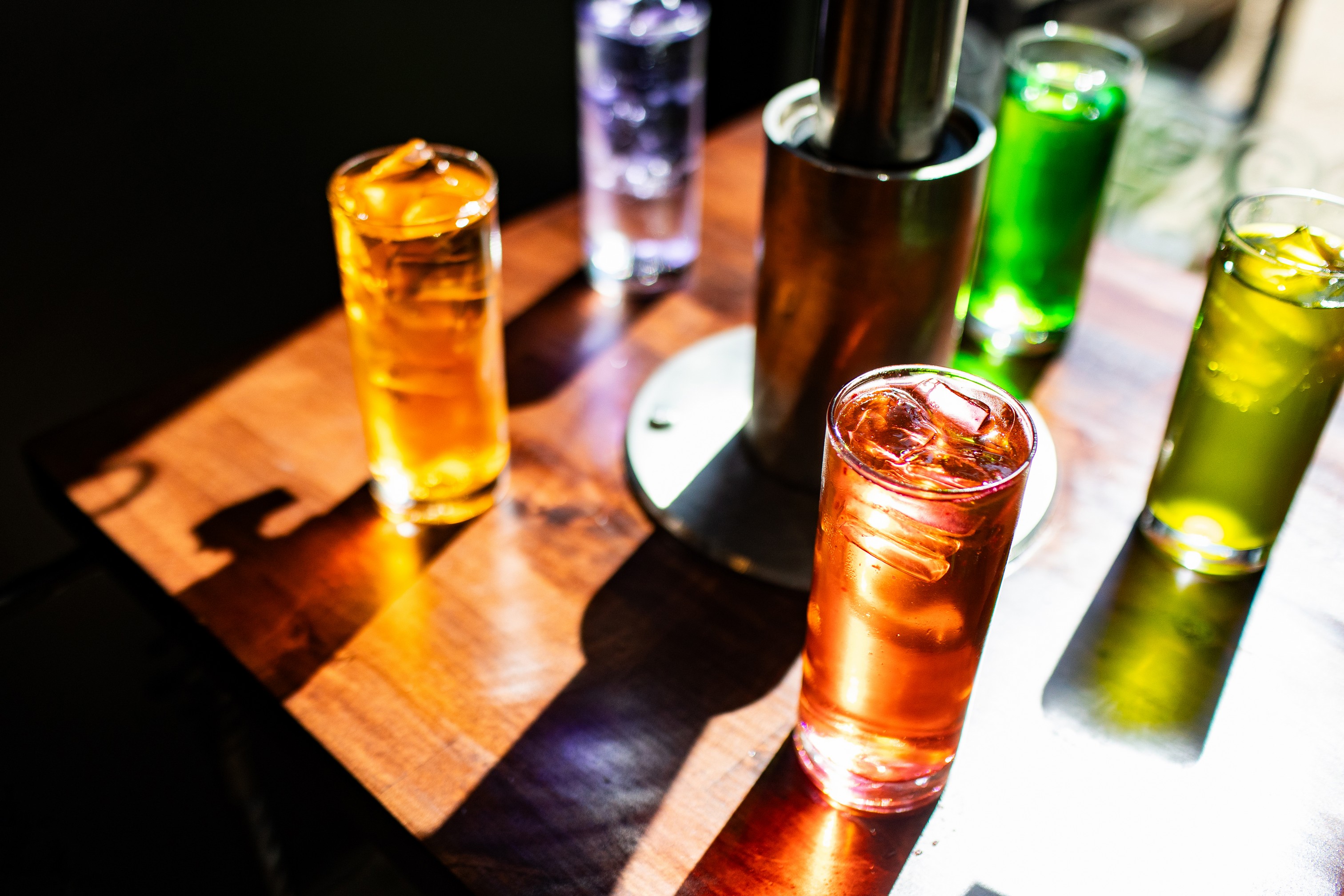 multicolored selection of 'supra sodas' soft drinks under aluminum drink dispenser