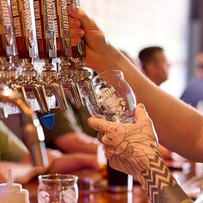 A person pours a draft beer from a brewery tap handle.