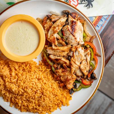 Grilled chicken fajitas with rice and a side of queso dip.