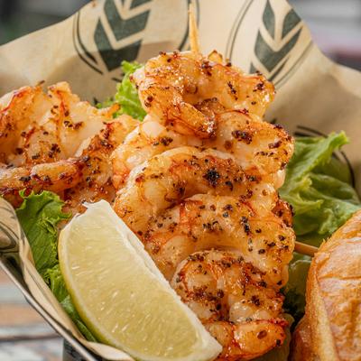 Grilled shrimp with lettuce and lemon wedge.