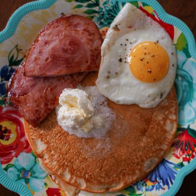 Savory pancakes topped with ham, melted butter, and a fried egg.