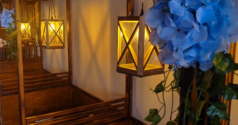 Restaurant booths, decorated with warmly lit lanterns and artificial greenery and flowers