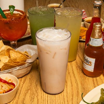 Glass of Horchata served with other drinks and dishes.