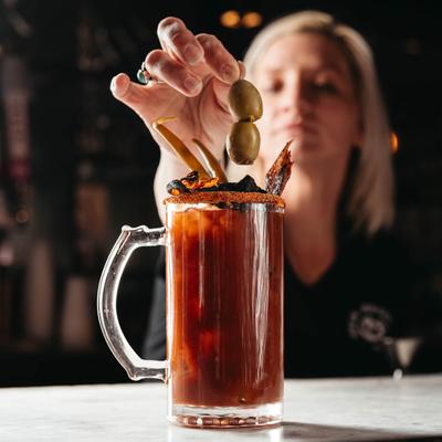 A person putting olive into a cocktail.