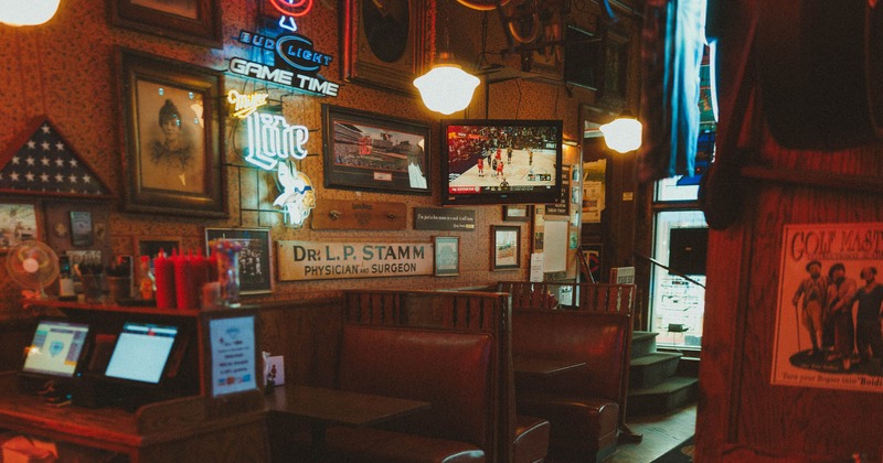 Interior, seating area, padded seating booths with tables, TV on the wall, various decoration