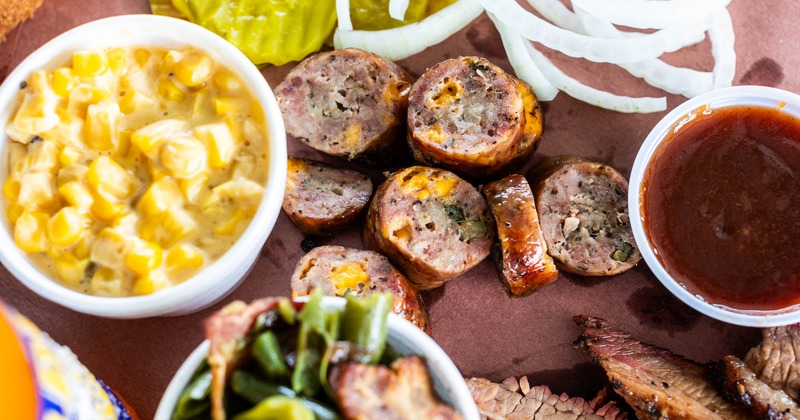 Sliced jalapeno cheese sausage, creamy corn, barbecue sauce, pickles, onions, and green beans