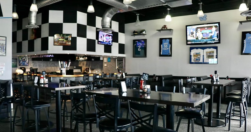 Interior of a sports bar with tables, chairs, TVs and sports memorabilia.
