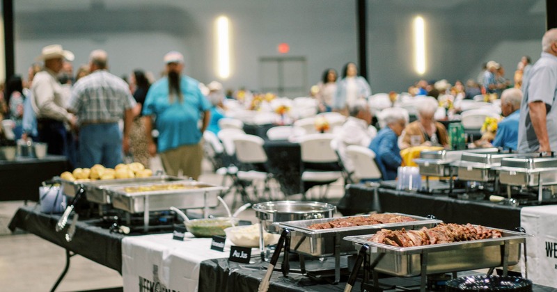Catering buffet with brisket trays at a crowded event