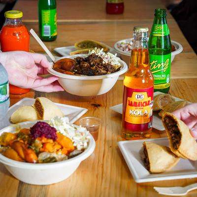 Assorted Caribbean dishes and soft drinks on a table.
