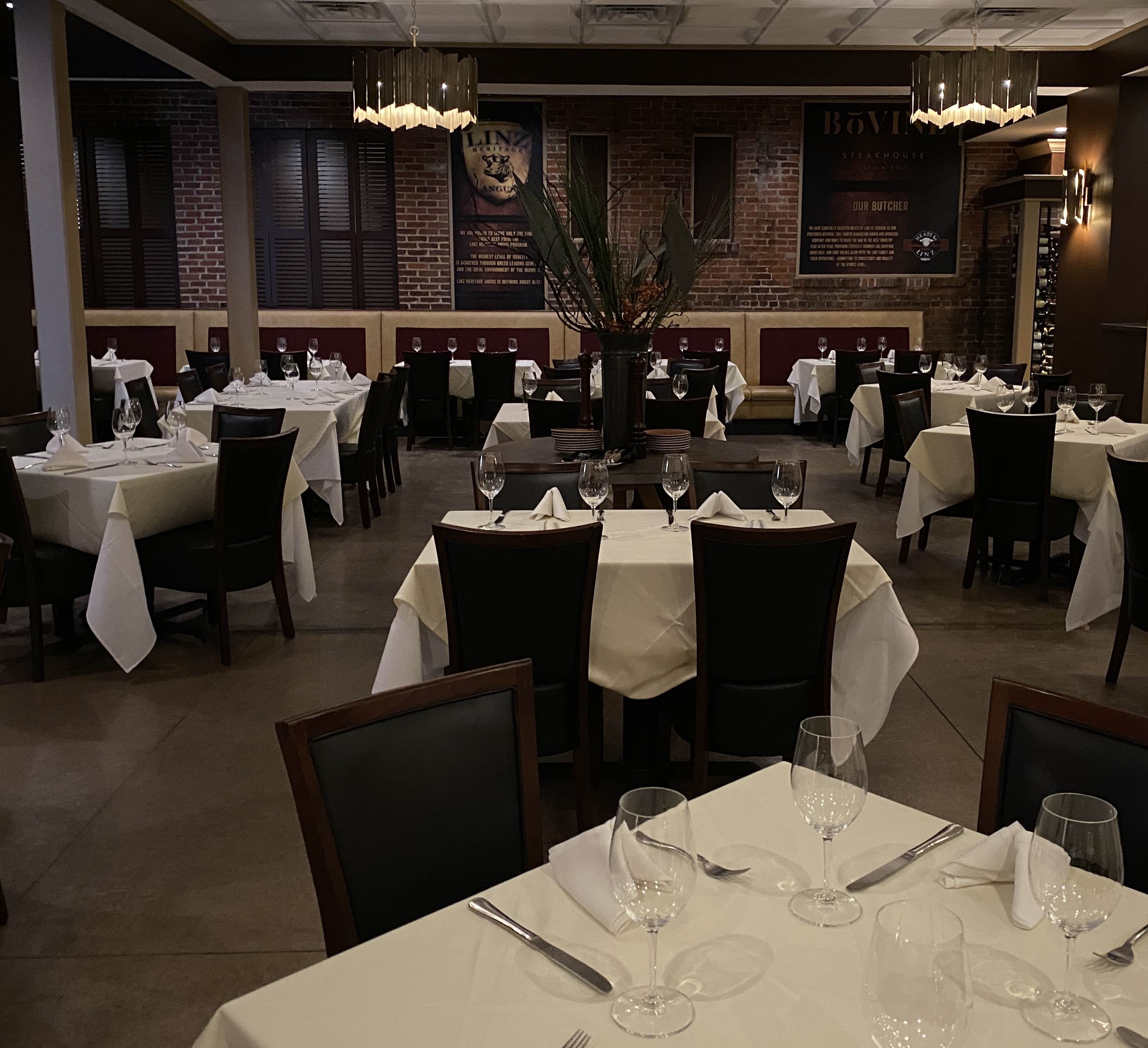 Wide view of the main ding room.  White table cloths and wine glasses set on tables.