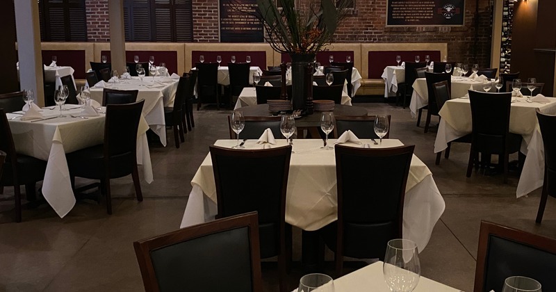 Wide view of the main ding room.  White table cloths and wine glasses set on tables.