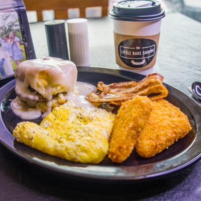 Sampler Platter with scrambled eggs, hash browns, bacon, and a biscuit with icing.