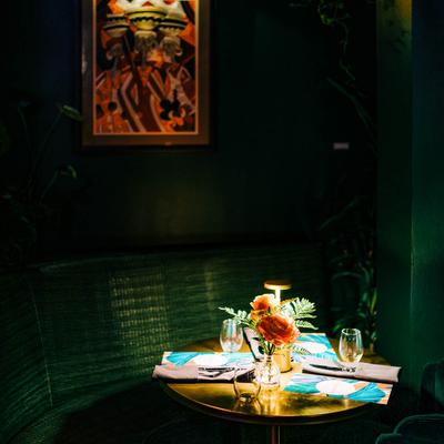 A cozy corner table with utensils, glasses, and menus under warm light.