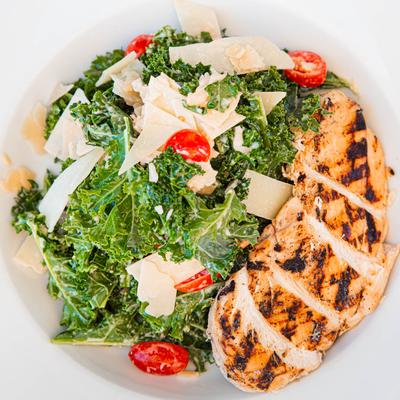 Kale Caesar salad, with grilled chicken, cherry tomatoes, parmesan, and Caesar dressing.