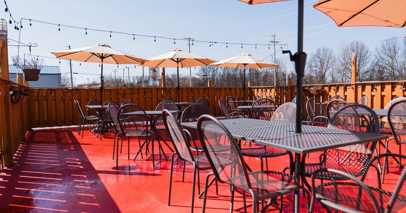 Exterior, partially covered seating area, tables and chairs, parasols, wooden railing