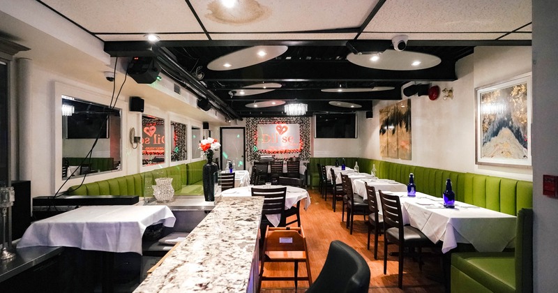 Interior, dining tables ready for guests, long banquette seating, pictures, mirrors