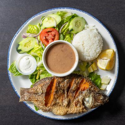 Fried fish with salad, rice, and beans.