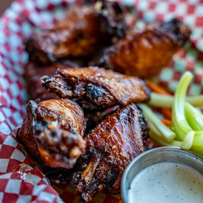 Fermented Hot Honey wings served with celery and bleu cheese dressing, extreme close up.