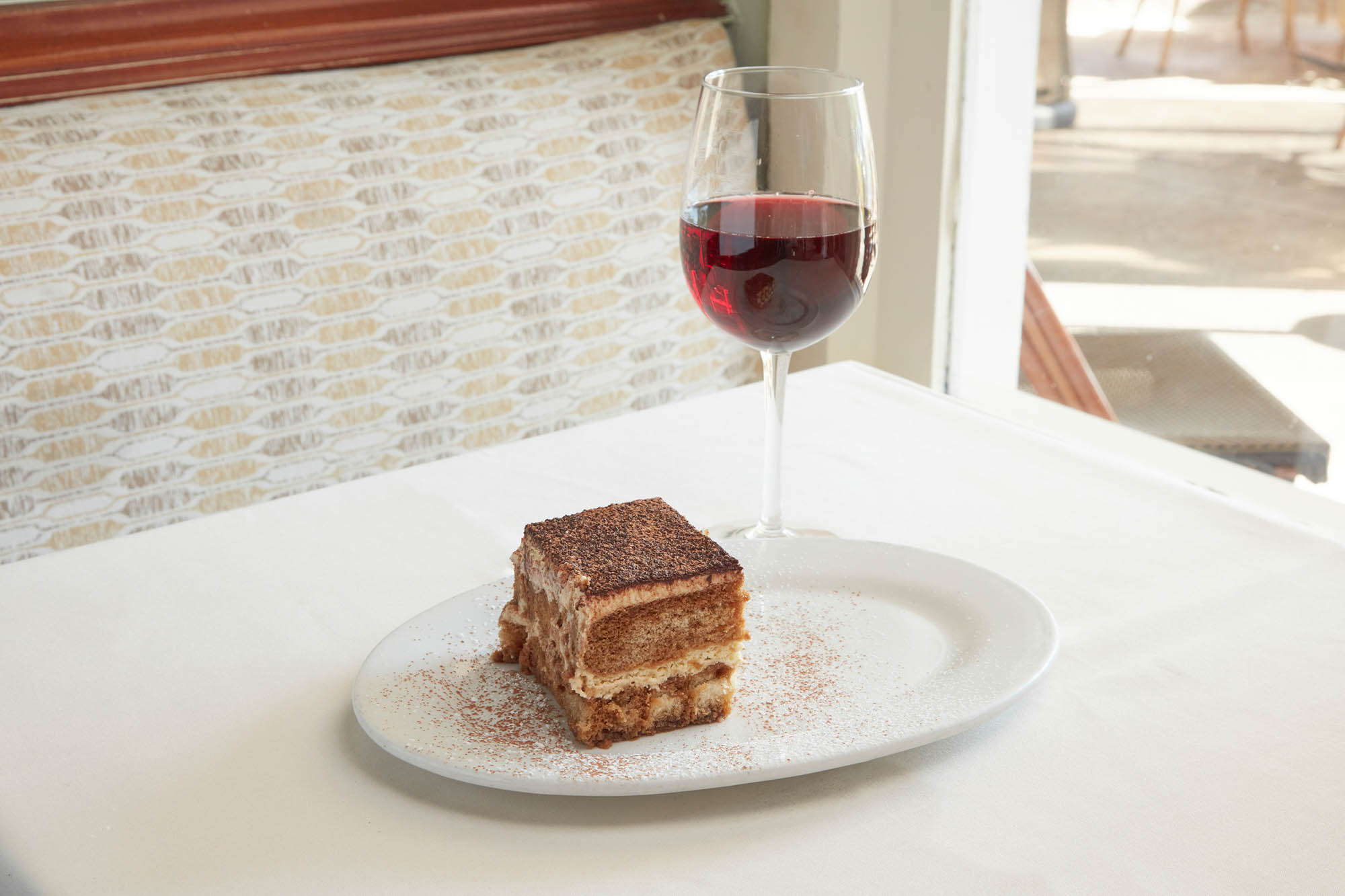Tiramisu and a glass of red wine served in a dining setting