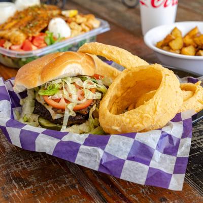 Mushroom Swiss Burger with onion rings alongside other dishes and a drink.