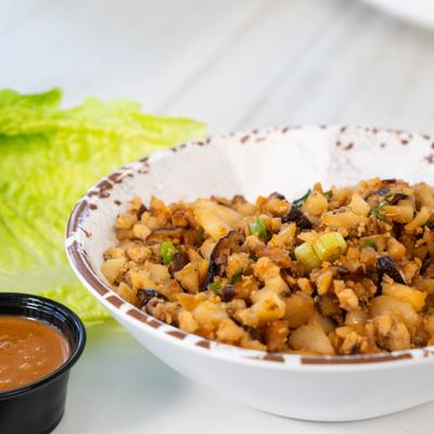 Chicken lettuce wraps served with a dipping sauce.