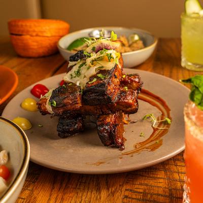 Grilled rib plate on a table with food and drinks.
