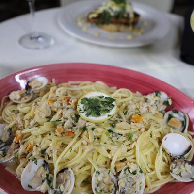 Spaghetti alle Vongole garnished with fresh herbs and a wheel of lemon.