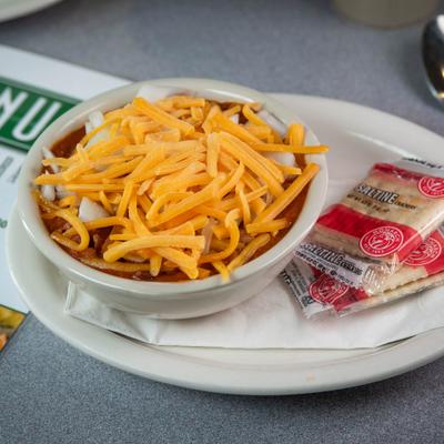 Chili bowl topped with shredded cheddar cheese and served with crackers.