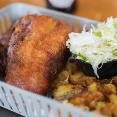 Crispy fried fish served with roasted potatoes and a side of coleslaw.