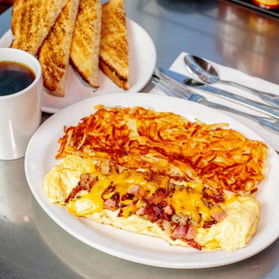 Meat lovers omelet with melted cheese and hashbrowns, accompanied with toast and coffee.
