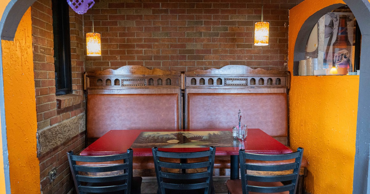 Dining setup featuring exposed brick walls, vintage wooden booth and hanging lights