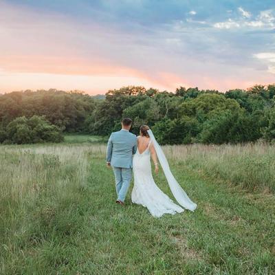 The bride and groom outside in the grass field.
