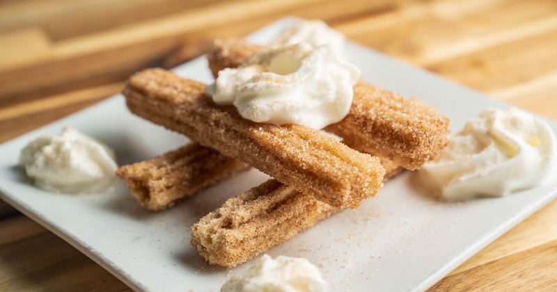 Cinnamon-sugar dusted churros served with whipped cream