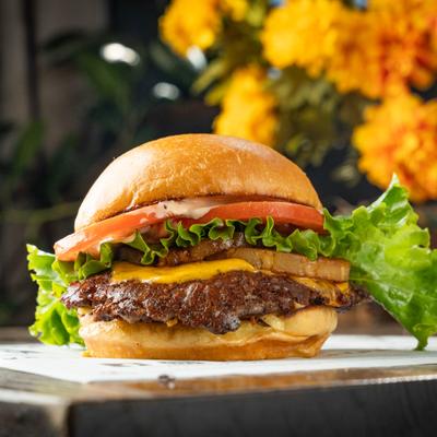 Bugrer topped with cheese, grilled pineapple, lettuce, tomato and sauce.