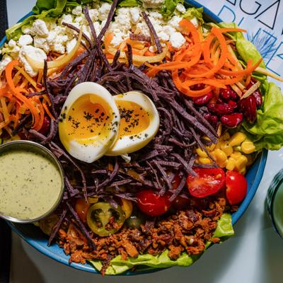 Cobb salad with red cabbage, beans, crispy bacon, corn, cheese, and egg.