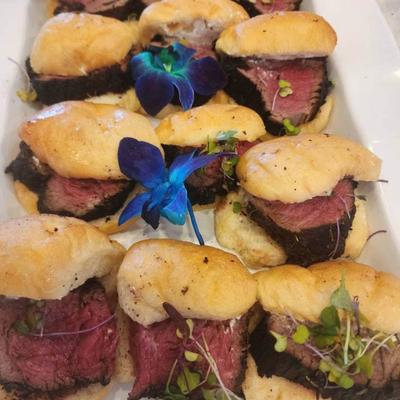 Medium-rare beef sliders with flower garnish.