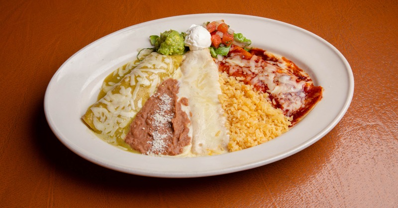 Trio Enchilada platter served with a side of rice, beans, guacamole and sour creme