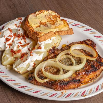 New York strip steak served with a piece of toast and baked potatoes with sour cream and bacon.