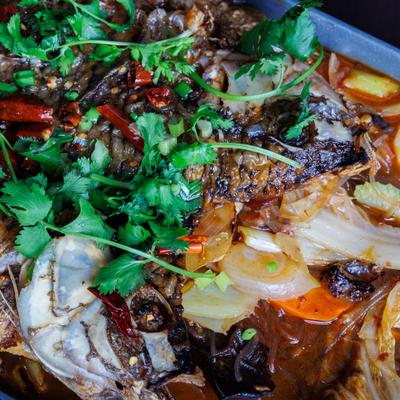 Spicy braised fish with chilies, vegetables, and cilantro in rich red sauce.