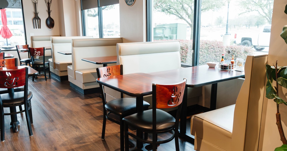 Restaurant interior with beige booths, wooden tables, and decorative wall elements