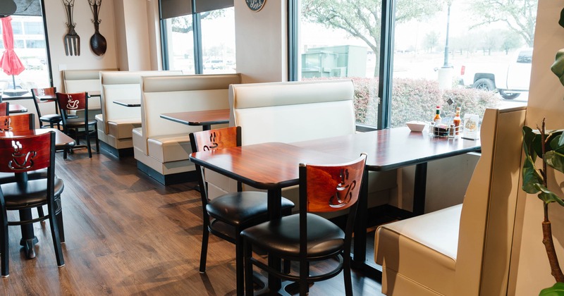 Restaurant interior with beige booths, wooden tables, and decorative wall elements