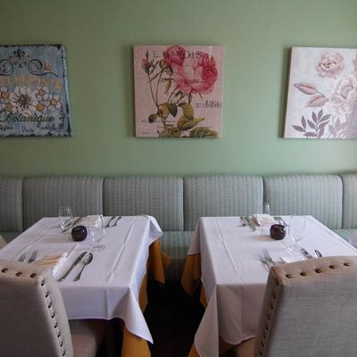 Interior, banquette with tables, wall decorated with pictures.