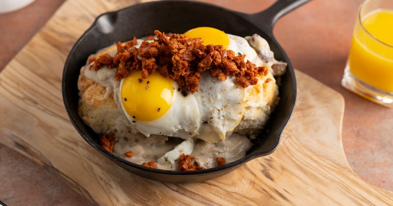 Skillet with biscuits, gravy, sunny side up eggs, and chorizo